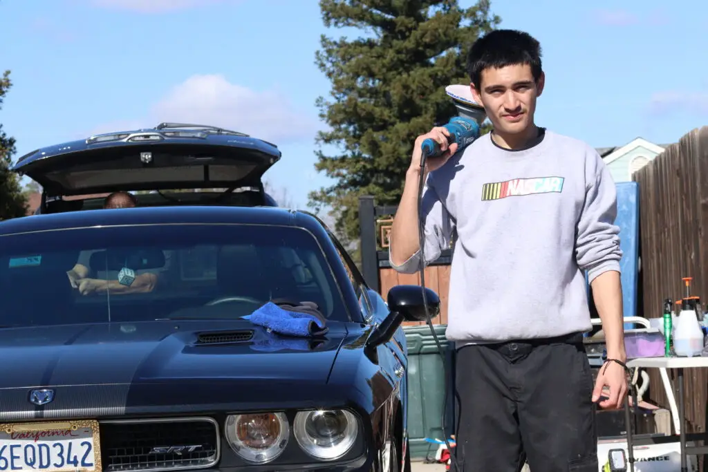 Khrome Auto Detailing owner with polisher standing next to Dodge Challenger SRT during professional paint correction in Fresno, CA.