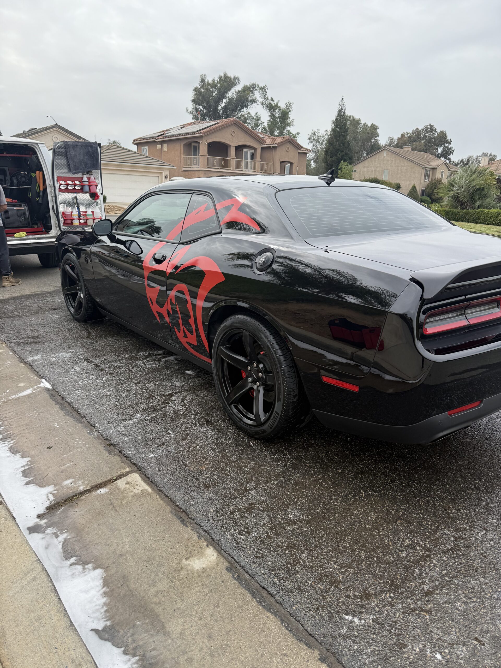 Black Dodge Challenger with red Hellcat graphic freshly detailed and ceramic coated by Khrome Auto Detailing in Fresno, CA — mirror-like gloss finish after professional exterior detailing service.
